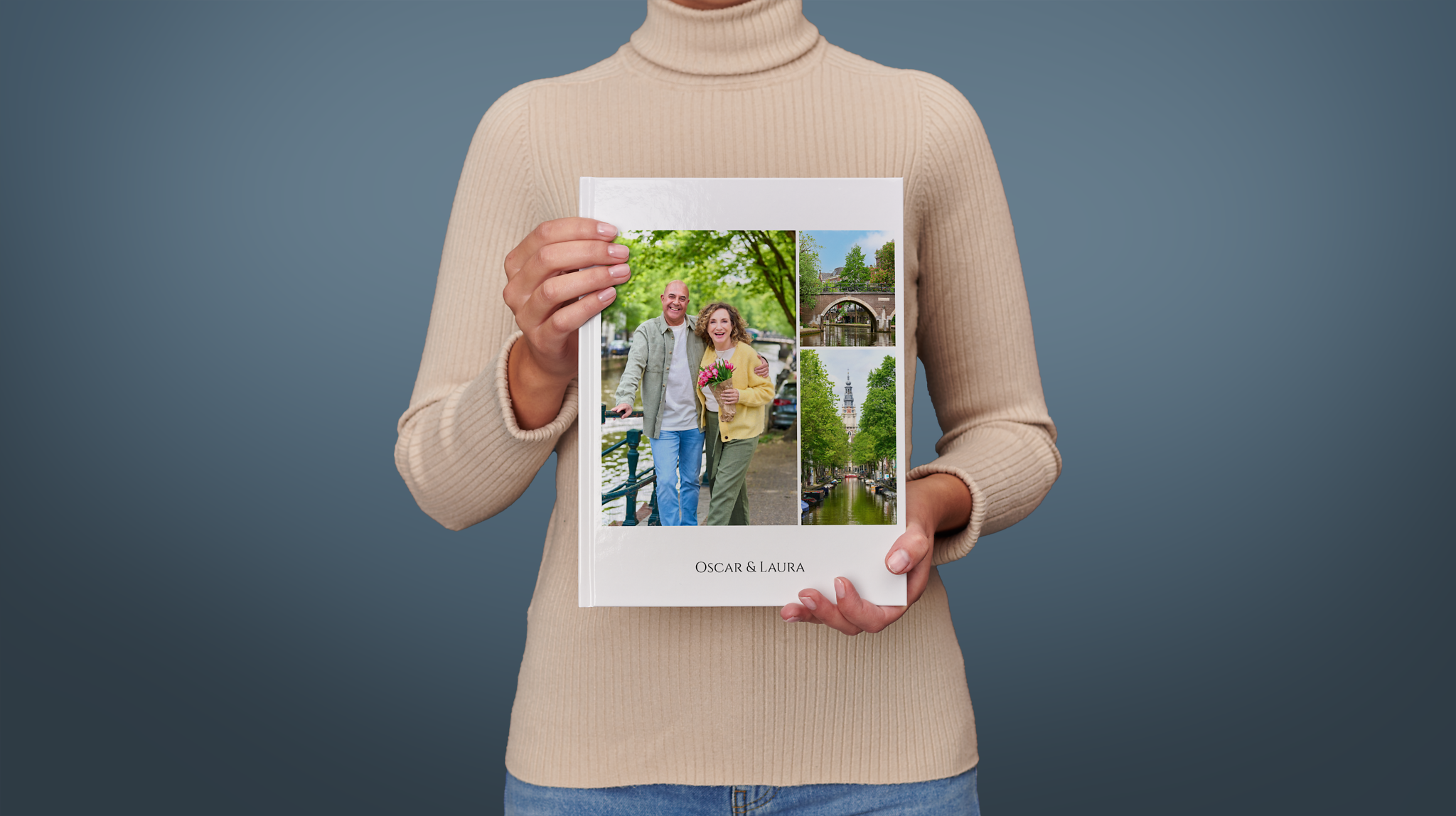 Una persona sujeta un álbum de fotos vertical Pixum con fotos de una pareja en Ámsterdam y el texto "Óscar & Laura"