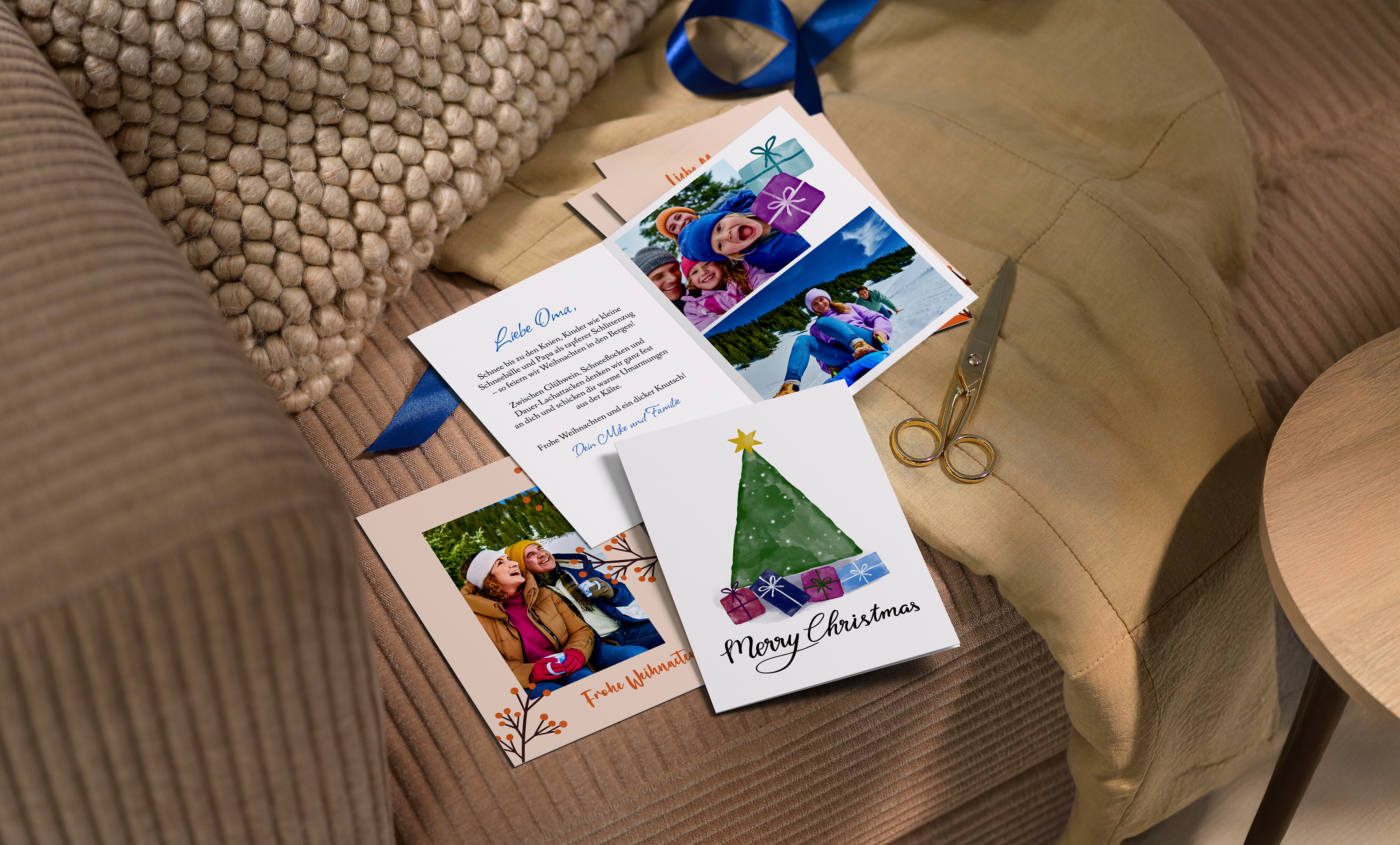 Mehrere Weihnachtskarten sind mit persönlichen Fotos gestaltet. Sie liegen gemeinsam mit Bastel-Materialien auf einer Couch.