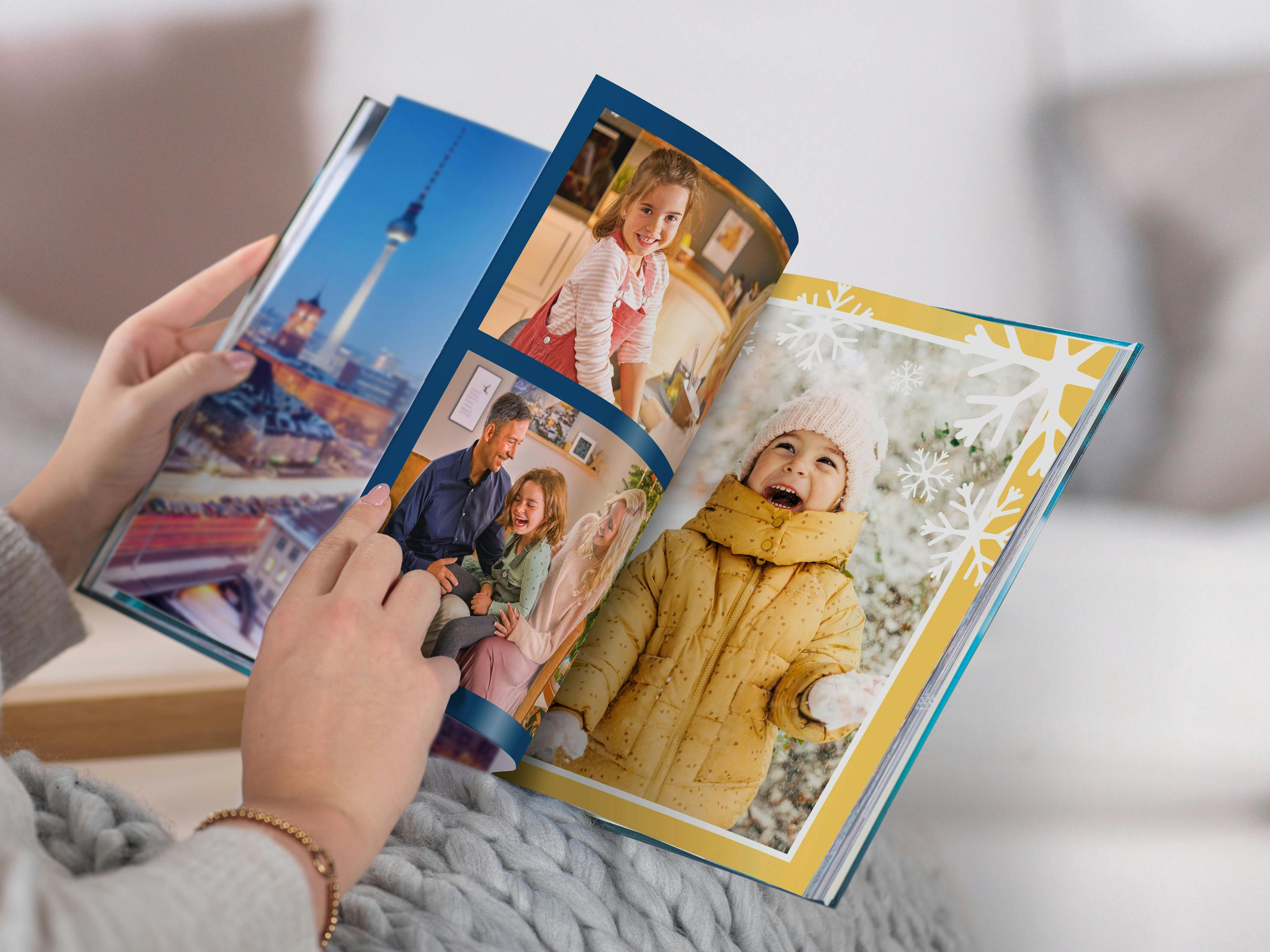 Een vrouw bladert door een Pixum Fotoboek met winterse familiefoto's