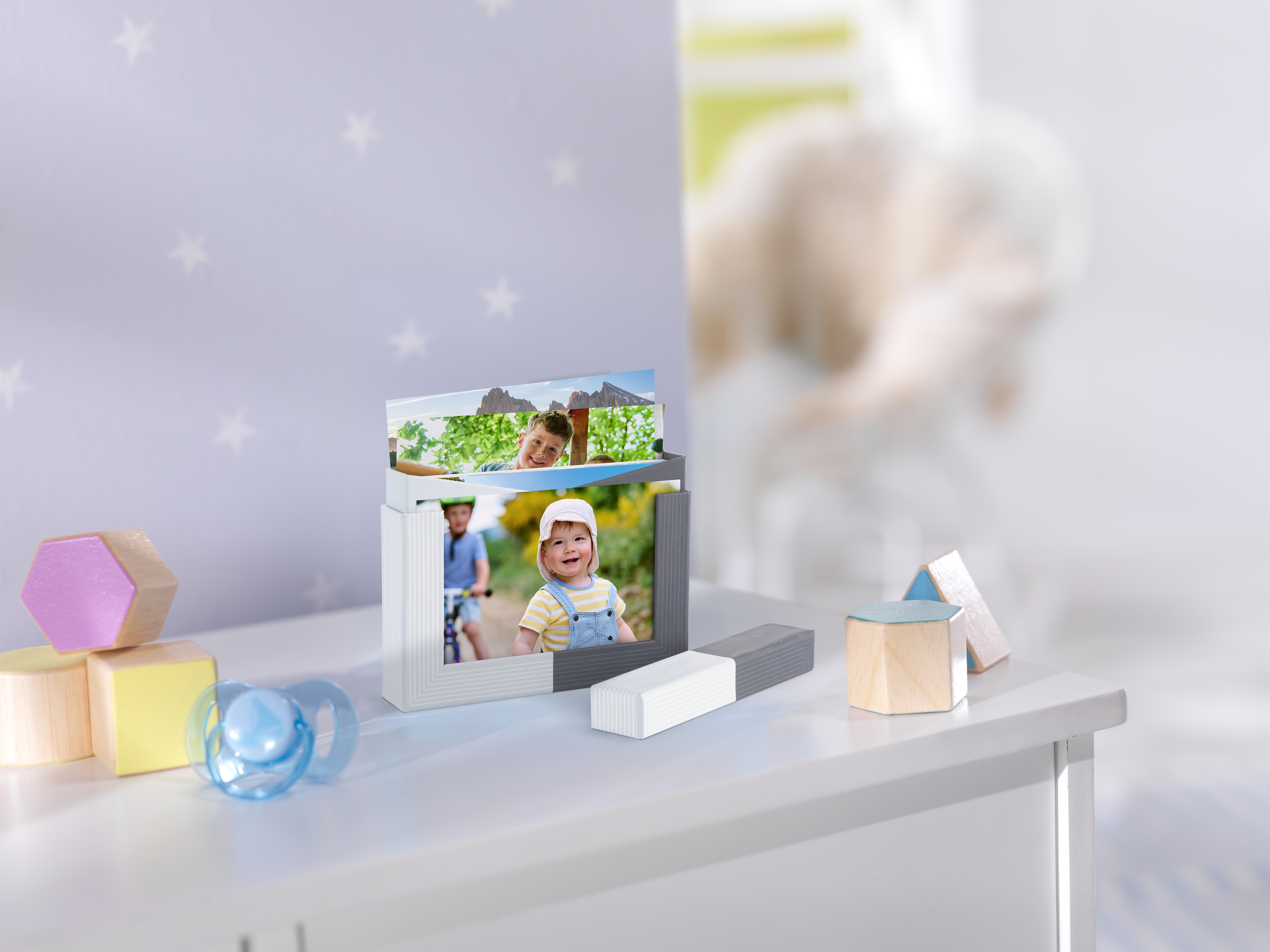 Eine Fotobox mit Rahmen ist mit verschiedenen Fotoabzügen von einer Familie mit Baby befüllt