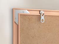 Metalen lijst wandbevestiging Een houten fotolijst hangt aan de muur met een metalen haakje zichtbaar aan de achterkant.