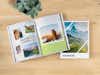Aufgeschlagenes Fotobuch im Hochformat mit Urlaubsbildern auf einem Holztisch
