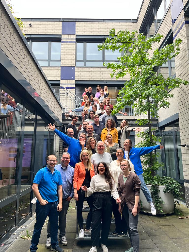 Medewerkers van Pixum op een trap op het binnenplein van het kantoor.