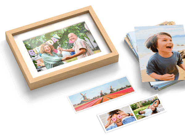 Ein Stapel Fotoabzüge, einzelne Fotostreifen und ein Foto im Rahmen mit sommerlichen Familienfotos