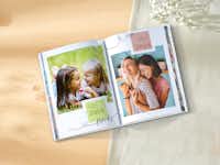 Ein Fotobuch über zwei Freundinnen liegt auf einem Tisch Ein Pixum Fotobuch im Hochformat mit Fotos von zwei Freundinnen liegt aufgeschlagen auf einem Tisch