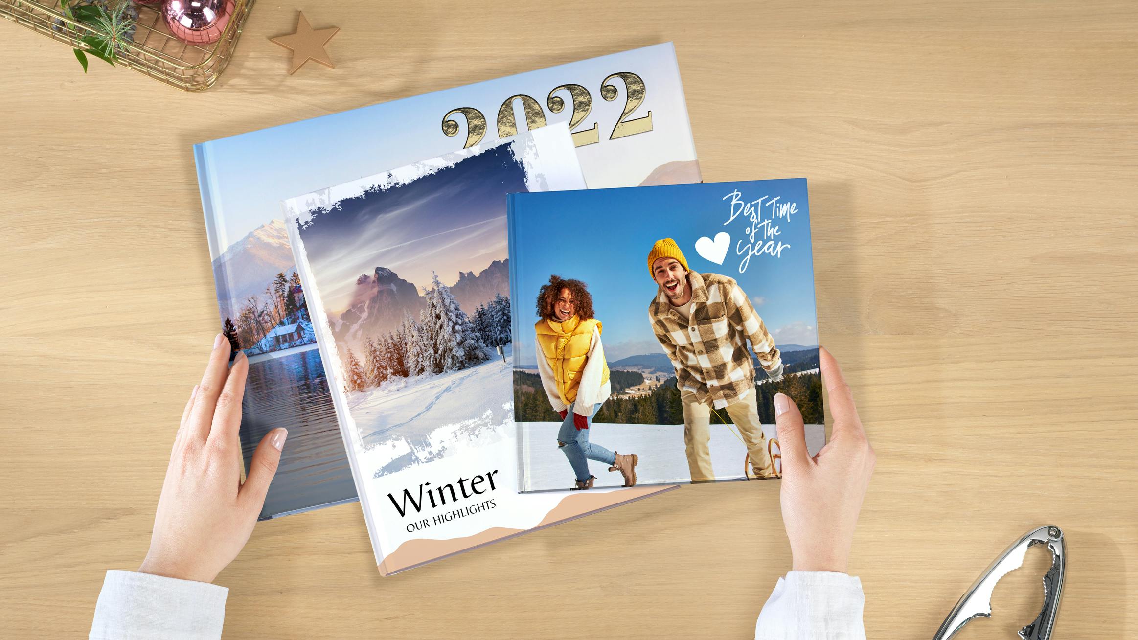 Verschiedene Pixum Fotobücher liegen auf einem Stapel. Die Cover sind unterschiedlich gestaltet uns zeigen winterliche Bildwelten.