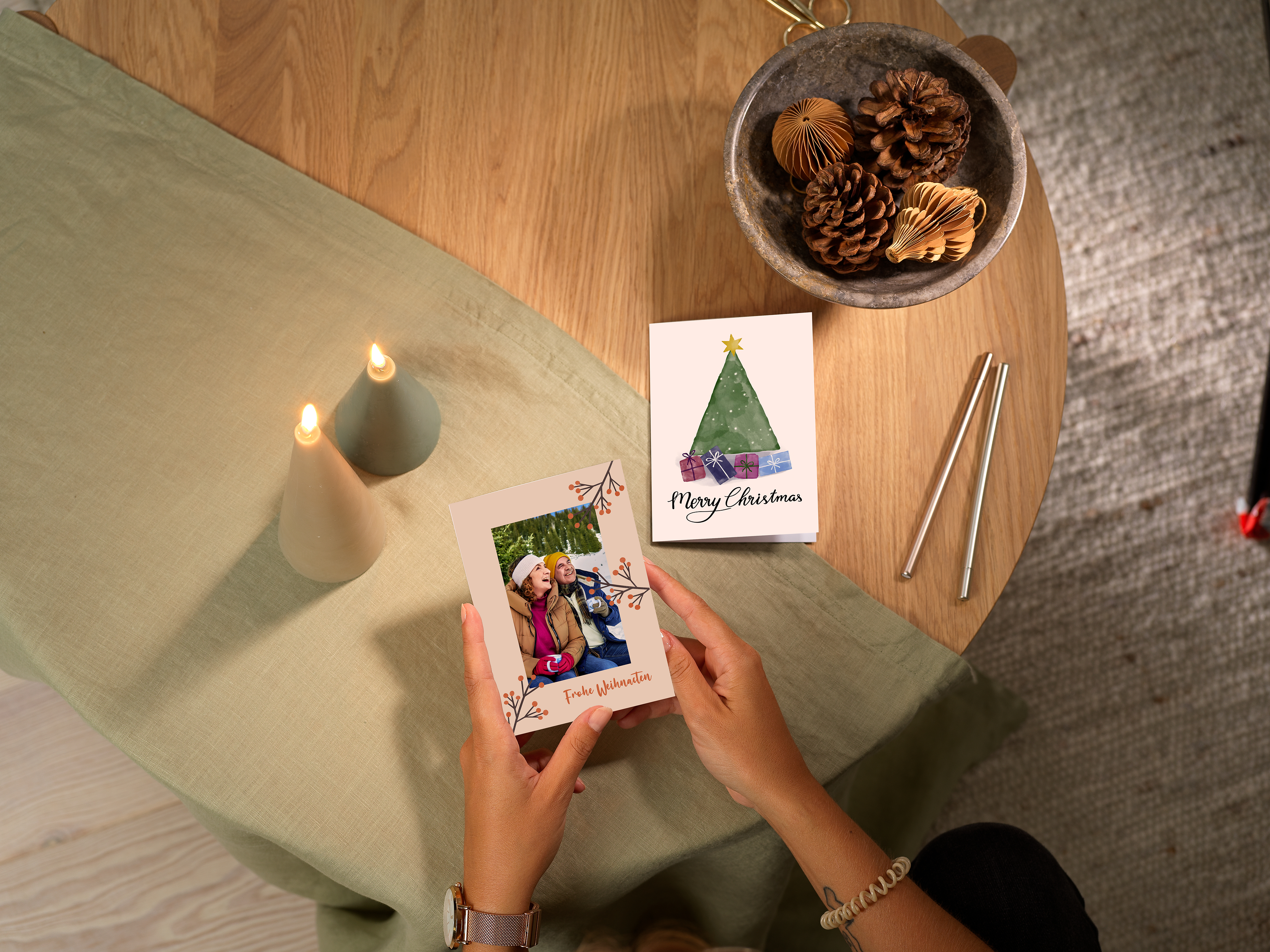 Deux cartes de vœux personnalisées avec des photos : l’une est tenue à la main, l’autre est posée sur une table.