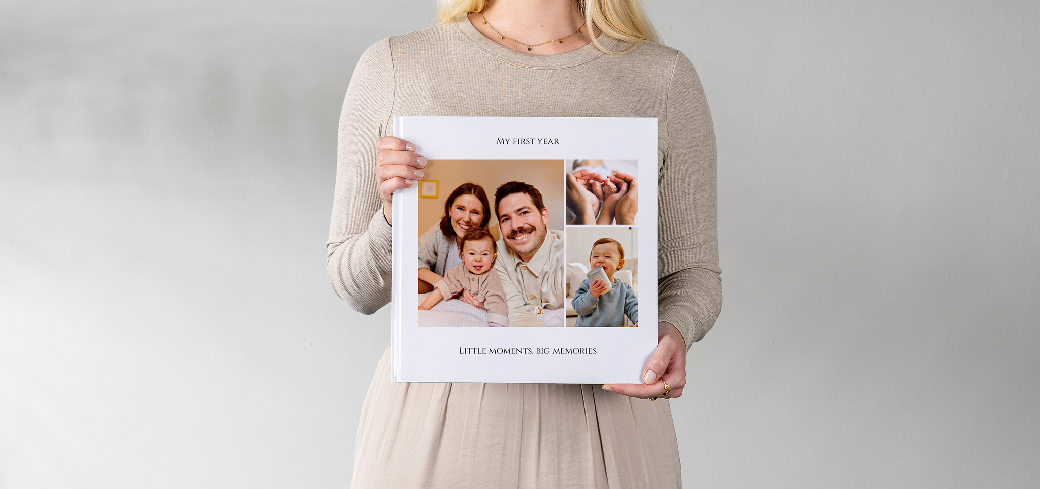 Ein als Babyalbum gestaltetes Fotobuch in XL wird von einer Frau gehalten. Auf dem Cover sind drei Bilder vom Baby und seinen Eltern zu sehen. 