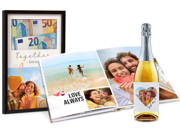 Huwelijkscadeaus met foto's Meerdere fotocadeaus voor een bruiloft staan naast elkaar: een fotolijst met geld, een Pixum Fotoboek en een fles met gepersonaliseerd etiket.