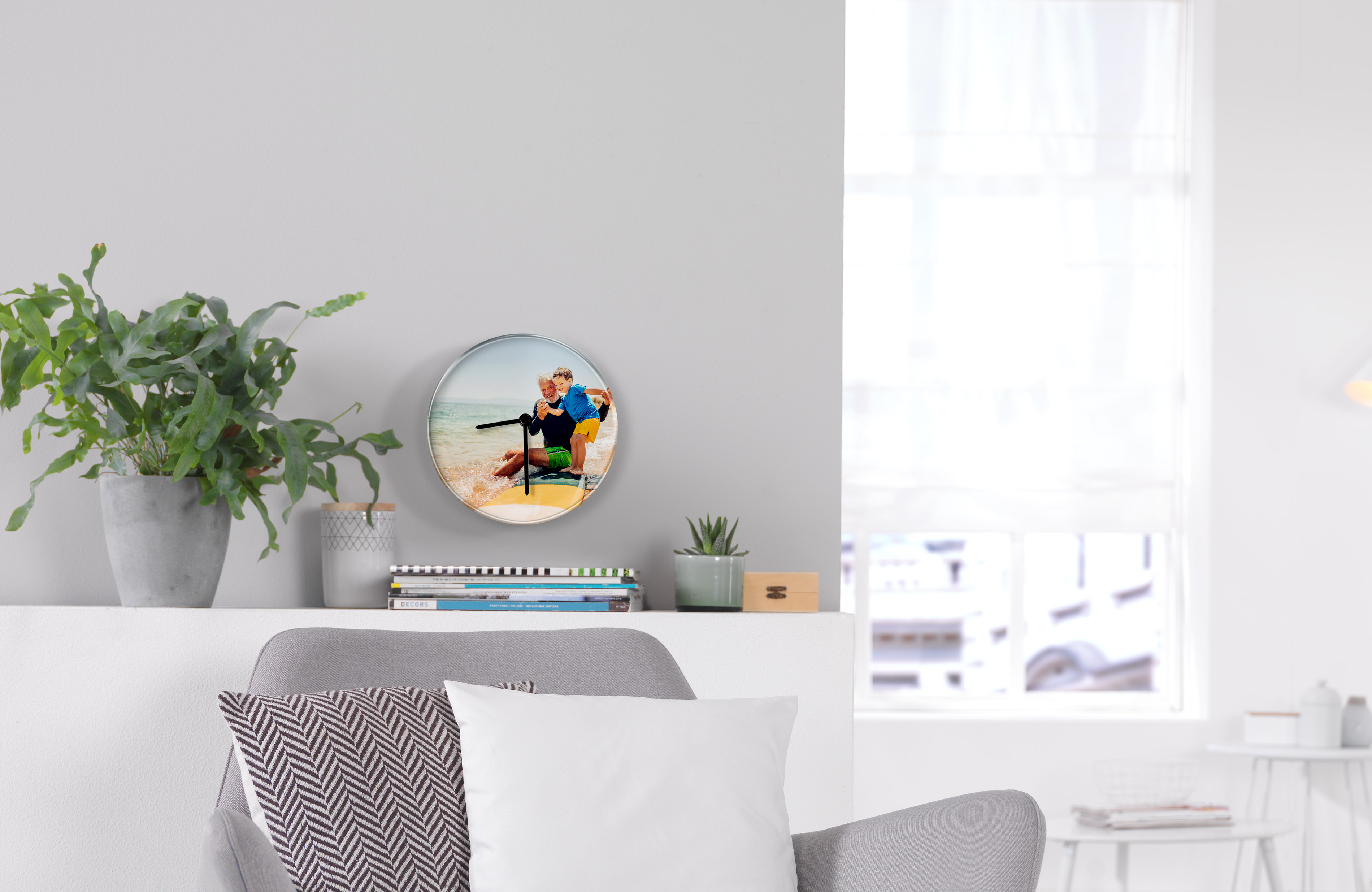 Fotouhr an einer Wand zeigt ein Urlaubsbild von Großvater und Enkel am Strand.