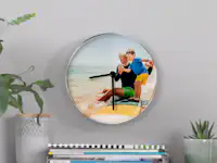 Reloj de pared personalizado con una foto de vacaciones Un reloj con foto en la pared muestra una foto de vacaciones de un abuelo y su nieto en la playa.