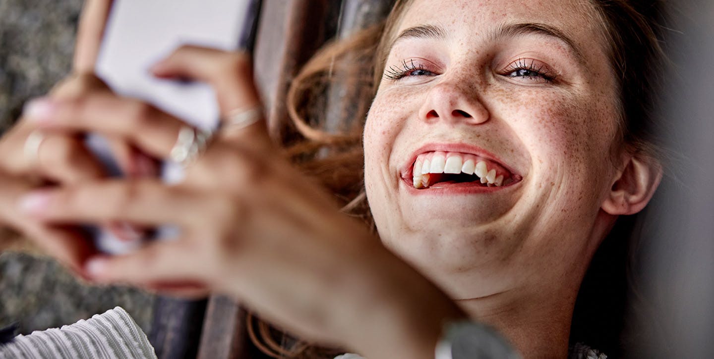 Jeune femme souriante qui tient un smartphone dans les mains