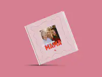 Fotobuch zum Muttertag gestalten Eine Person hält ein Fotobuch in der Hand. Dieses ist mit rosafarbenen Elementen zum Muttertag gestaltet.