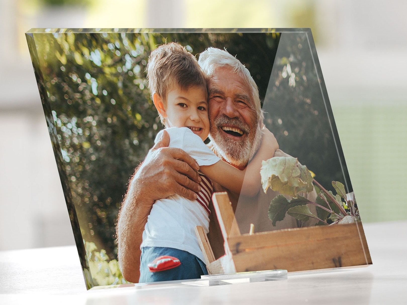 Photo sur plexiglas avec un grand-père et son petit-fils qui s'enlacent joyeusement dans un jardin ensoleillé, souriant chaleureusement.