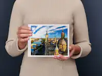 Fotoboek klein liggend Een persoon in een beige trui houdt een fotoboek vast met daarop een lavendelveld met een boom en een huisje bij zonsondergang.