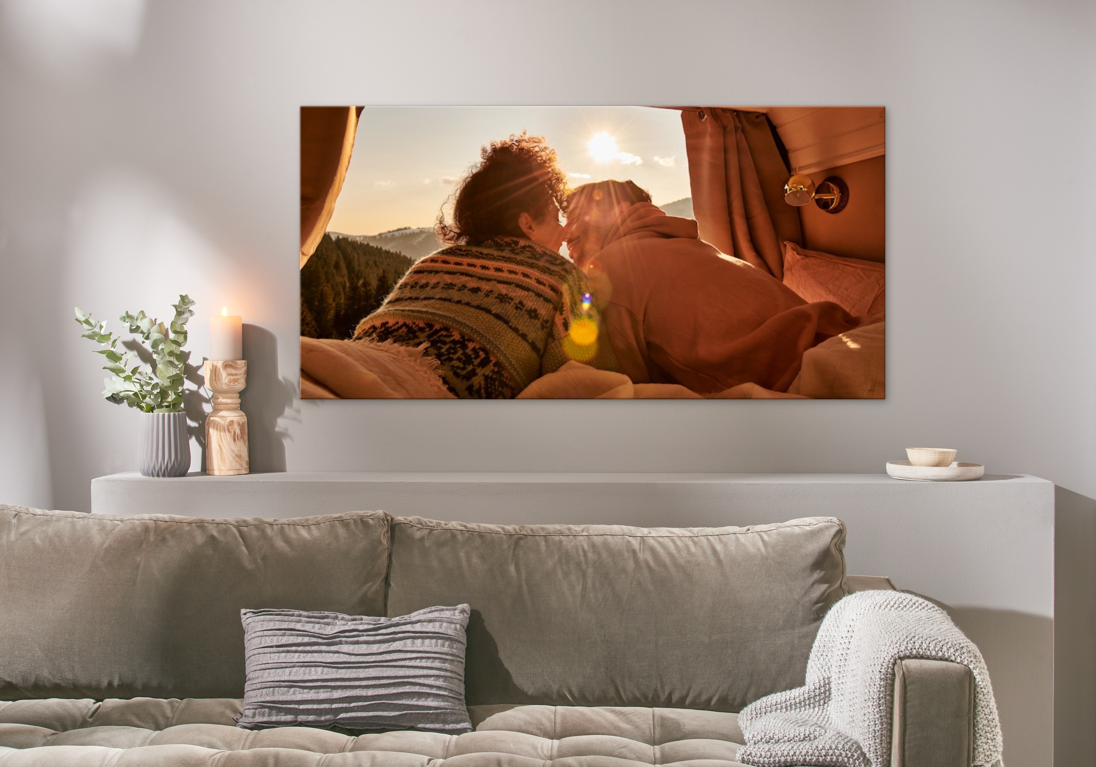Eine Fotoleinwand hängt über einem Sofa und zeigt ein Bild von einem glücklichen Pärchen in einem Camper.