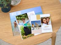 Pixum Fotobücher als Jahresrückblick gestalten Mehrere Fotobücher liegen übereinandergestapelt auf einem Tisch