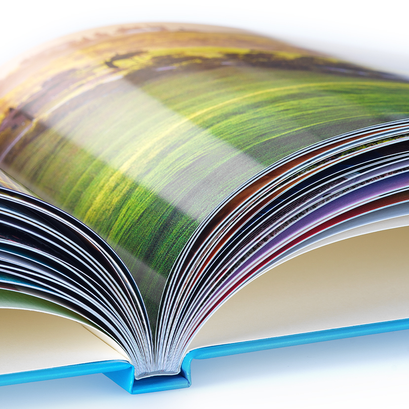 Freisteller eines aufgeschlagenen Fotobuchs mit Detailansicht des Premiumpapiers glänzend