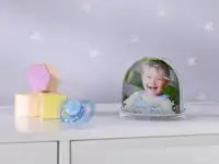 Schneekugel mit einem Kinderfoto Schneekugel mit einem Foto von einem kleinen Kind steht in einem Kinderzimmer