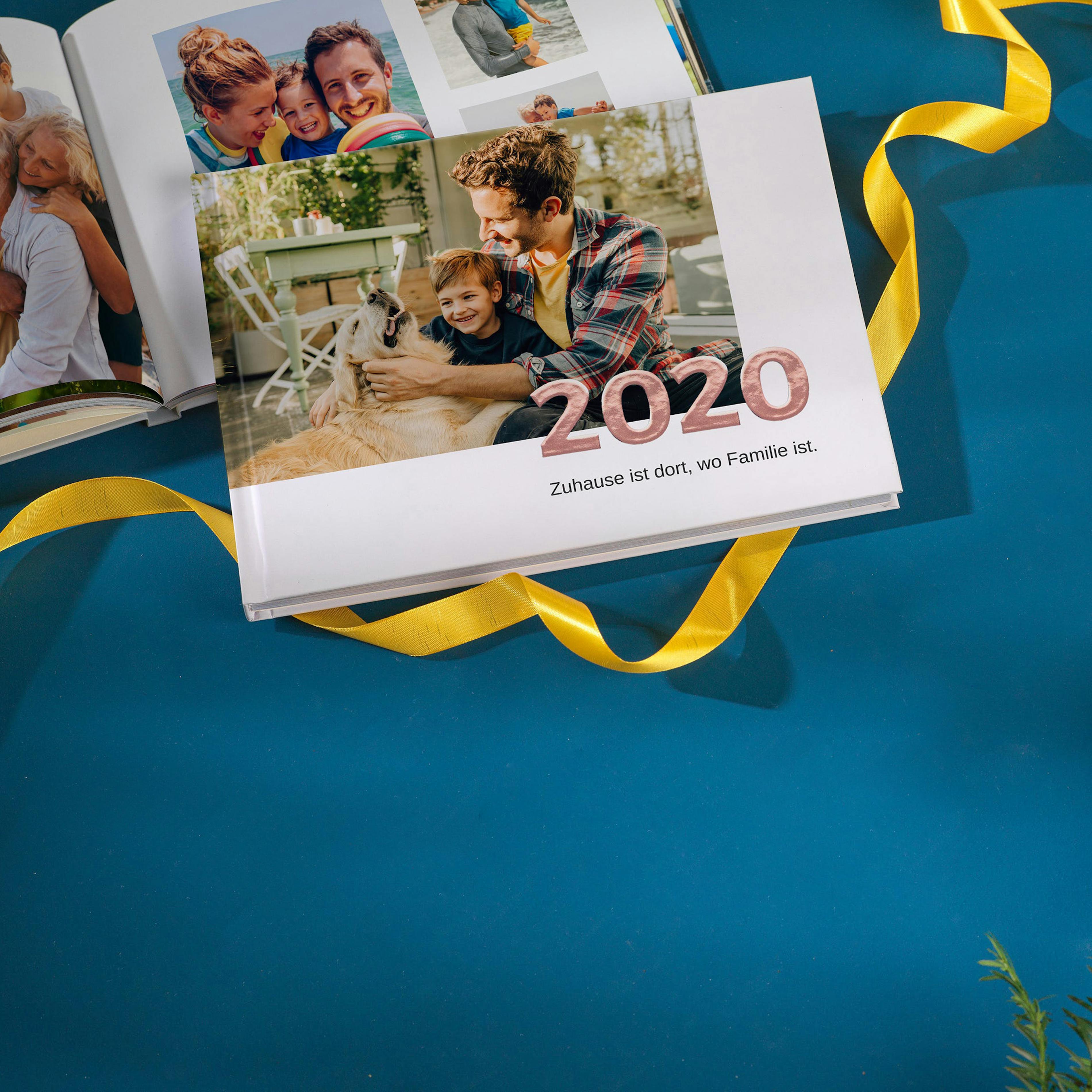 Pixum Fotobuch erstellen Pixum Fotobuch als Jahrbuch von 2020 auf einem blauen Tisch