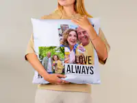 Fotokissen 50x50 mit einer Fotocollage von einem älteren Ehepaar Fotokissen 50x50 cm wird in einer Hand gehalten. Es ist mit einer Foto-Collage von einem älteren Ehepaar und dem Schriftzug 'Love always' gestaltet.