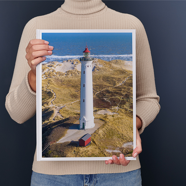 En kvinde holder en XXL fotobog i højformat med et stort landskab i sine hænder