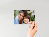 Fotoabzug 10 cm Hand, die einen 10 Fotoabzug vor einem neutralen Hintergrund hält, mit einem Familienfoto.