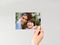 Fotoafdruk 10 cm Hand die een fotoafdruk van 10 cm met daarop een familie vasthoudt voor een neutrale achtergrond