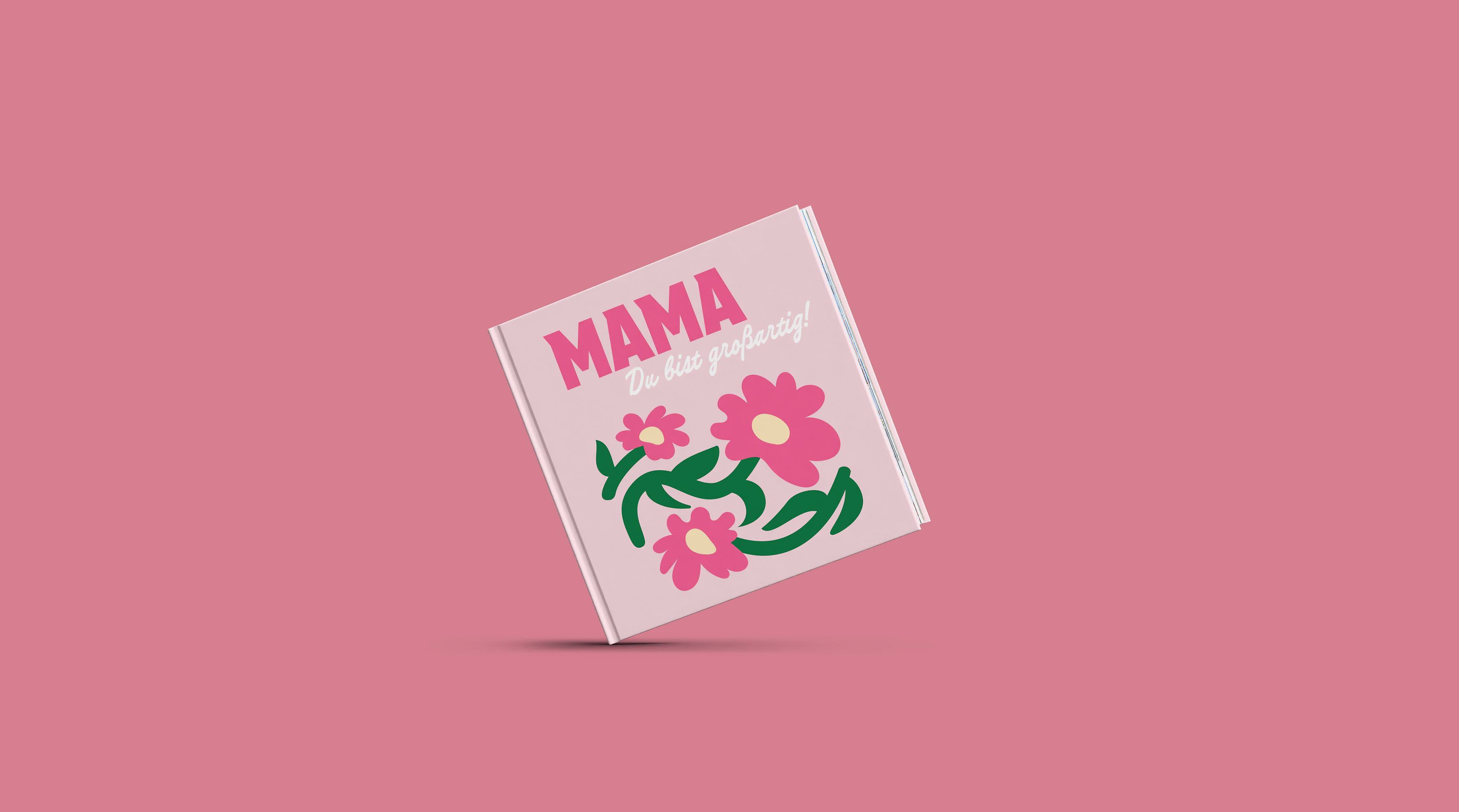 Eine Person hält ein Fotobuch in der Hand. Dieses ist mit rosafarbenen Elementen zum Muttertag gestaltet.