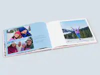 Fotobuch zum Geburtstag mit Familienfotos Fotobuch zum Geburtstag mit Familienfotos. Die linke Fotobuchseite ist mit Fotos von den Kindern und den Eltern gestaltet und hat einen blauen Hintergrund und Schrift neben den Fotos. Auf der rechten Seite ist ein Portraitfoto auf weißem Hintergrund.