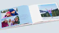 Fotobuch zum Geburtstag mit Familienfotos Fotobuch zum Geburtstag mit Familienfotos. Die linke Fotobuchseite ist mit Fotos von den Kindern und den Eltern gestaltet und hat einen blauen Hintergrund und Schrift neben den Fotos. Auf der rechten Seite ist ein Portraitfoto auf weißem Hintergrund.