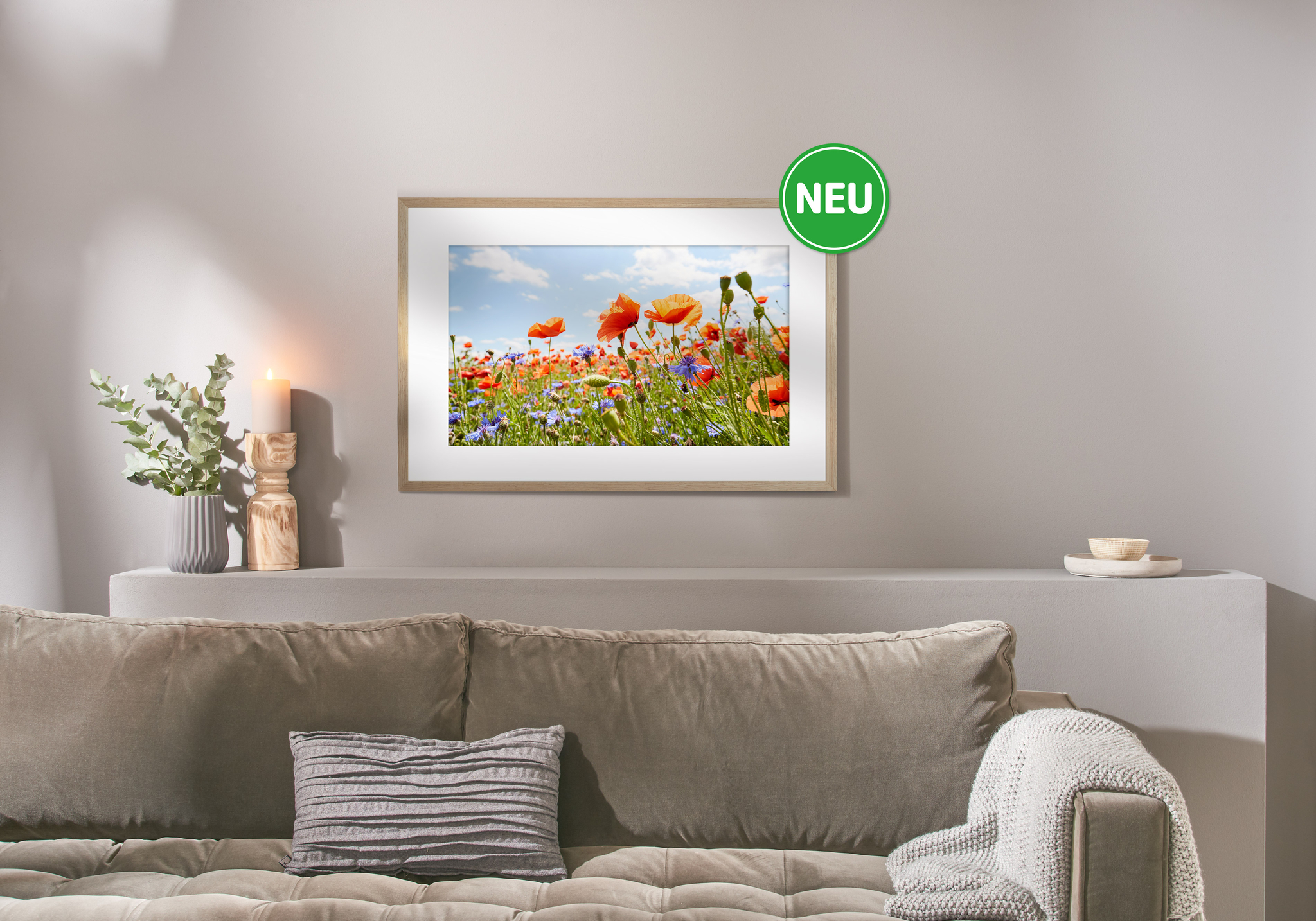 Bild einer roten Mohnwiese im Eicherahmen an einer grauen Wohnzimmerwand mit grünem Störer