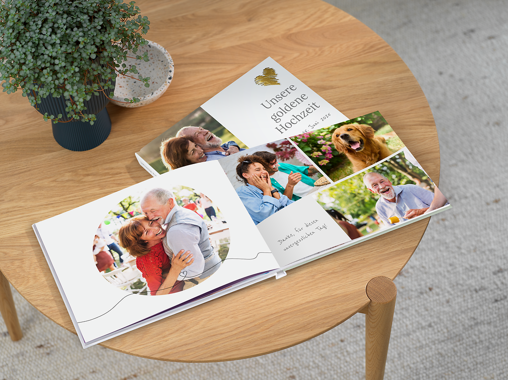Fotobuch zur goldenen Hochzeit liegt geöffnet auf einem runden Holztisch. Im Fotobuch sind fröhliche Erinnerungsfotos, festliche Dekoration und handgeschriebener Text zu sehen.