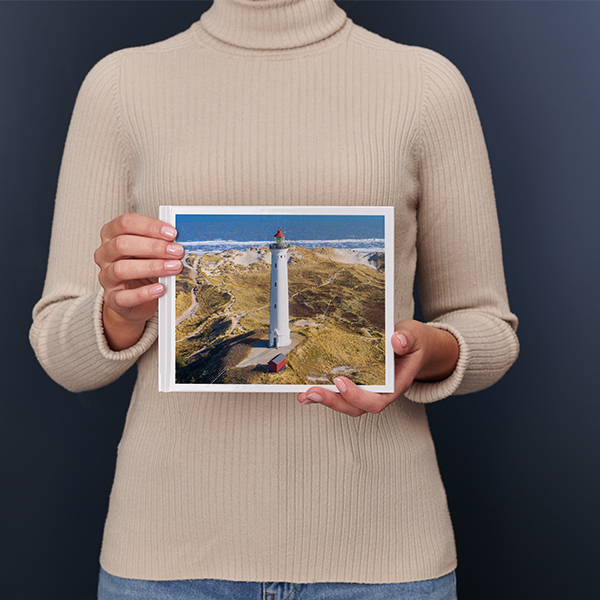 Una donna regge un Fotolibro Pixum piccolo panoramico
