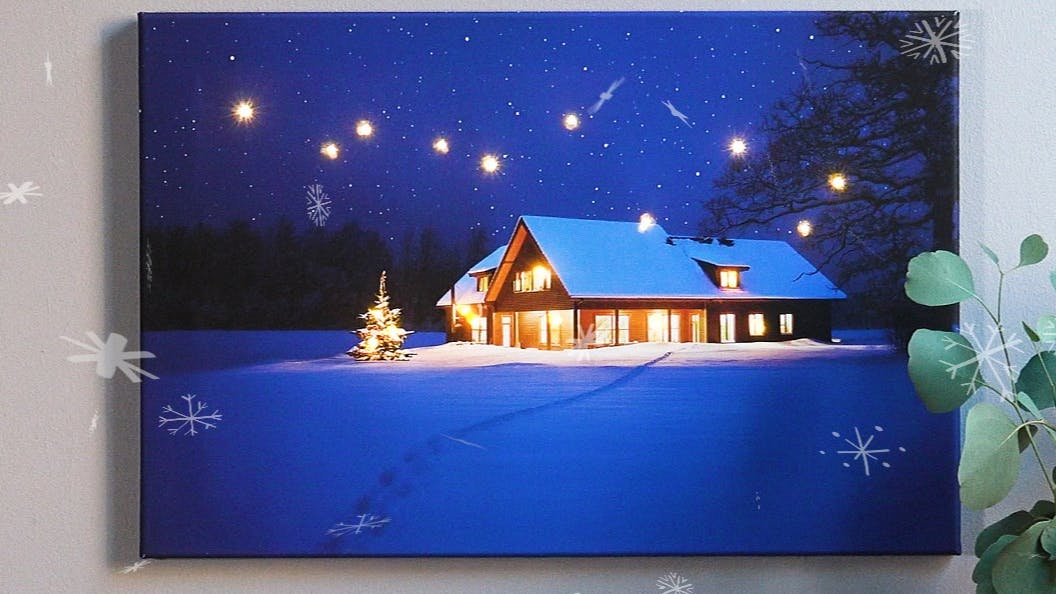 Beleuchtete Fotoleindwand mit schneebedecktem Haus drauf
