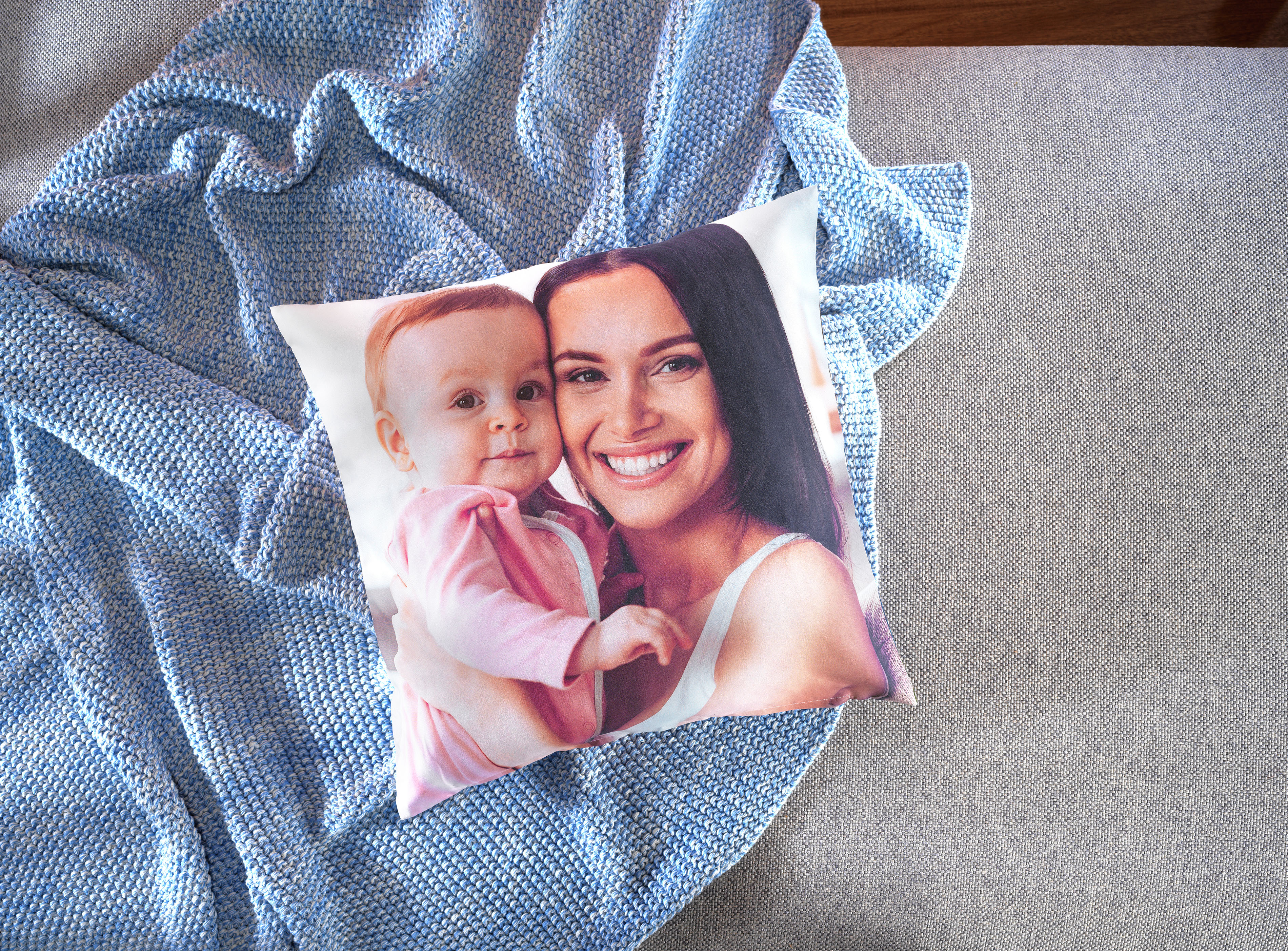 Een kussen met daarop een foto van een moeder en baby.