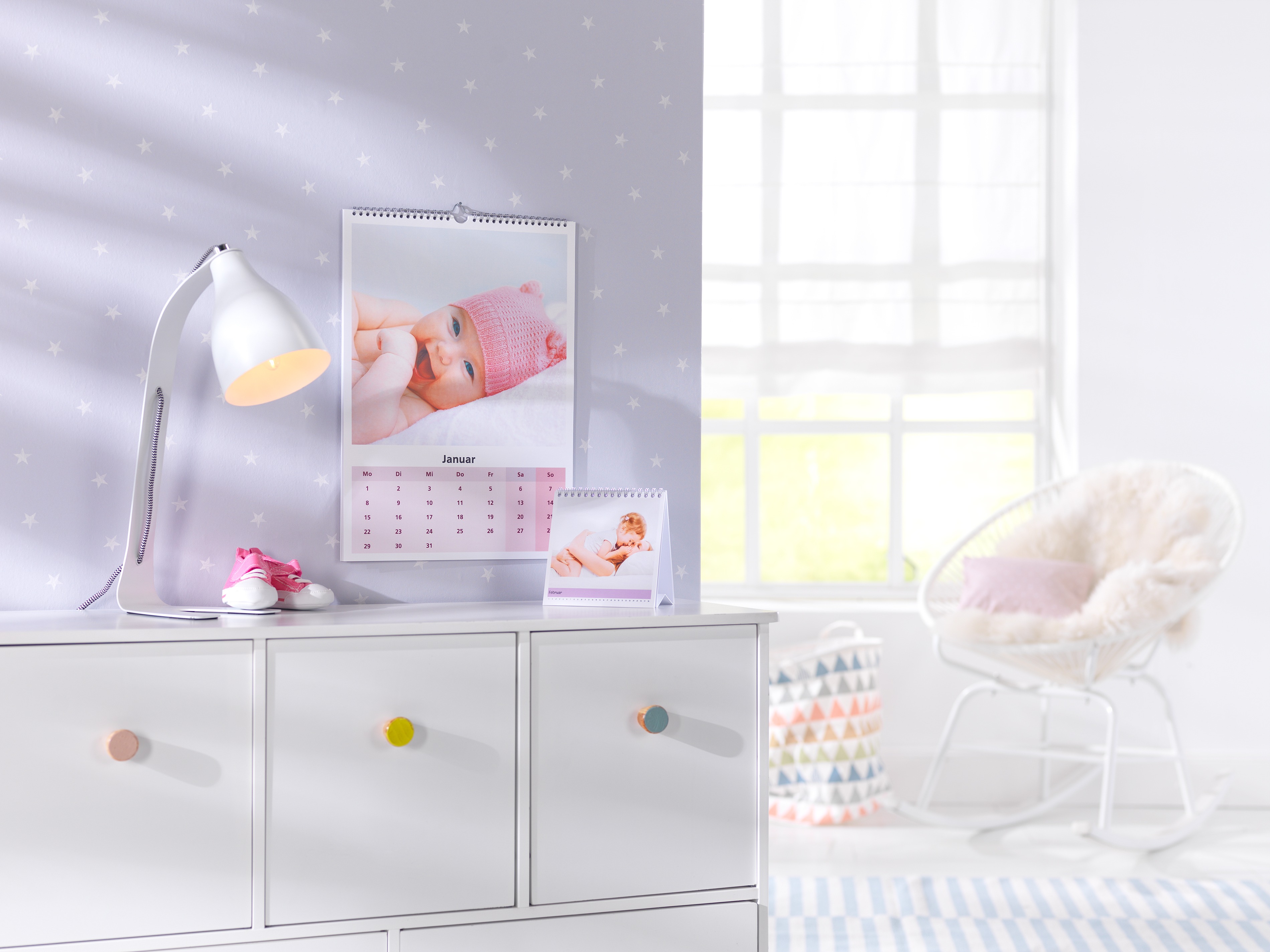 Een fotokalender met een foto van een baby hangt aan de muur van een kinderkamer.