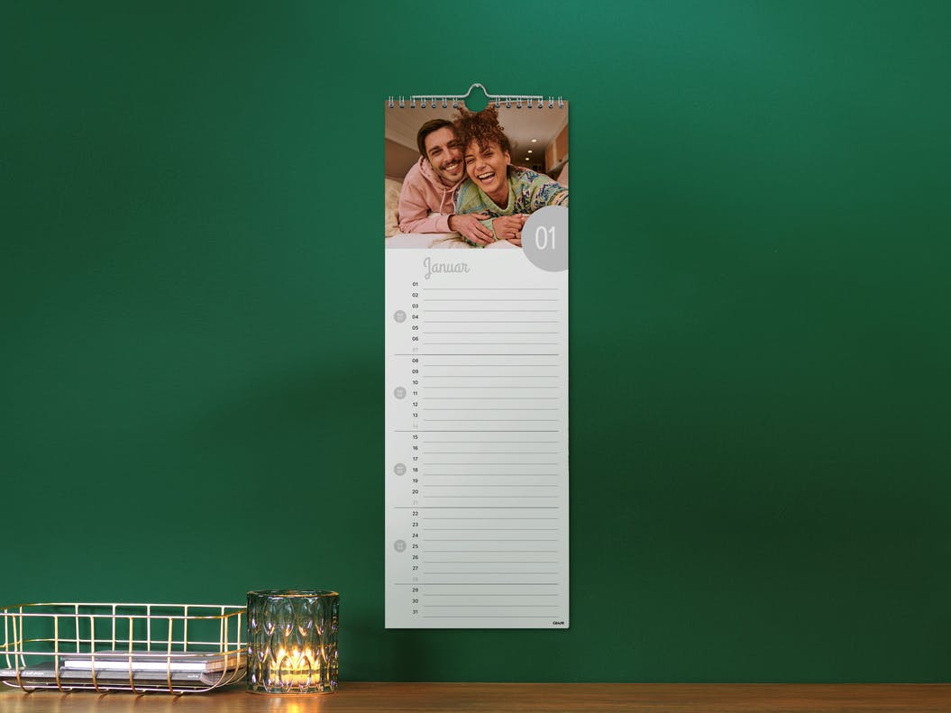 Calendario de cocina grande en una pared verde con la foto de una pareja
