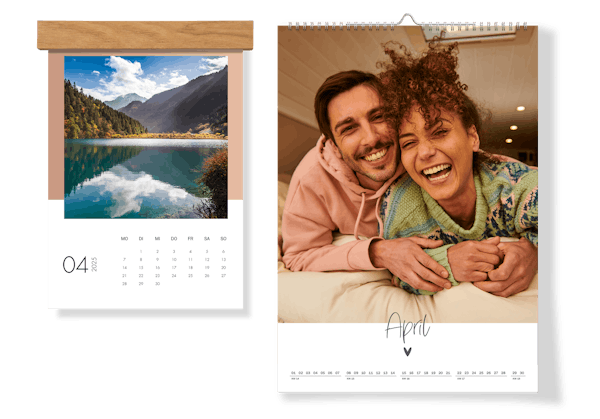 Dos calendarios de pared puestos uno al lado del otro. Uno tiene un colgador de madera y la foto de un paisaje y el otro una foto de pareja sin colgador de madera