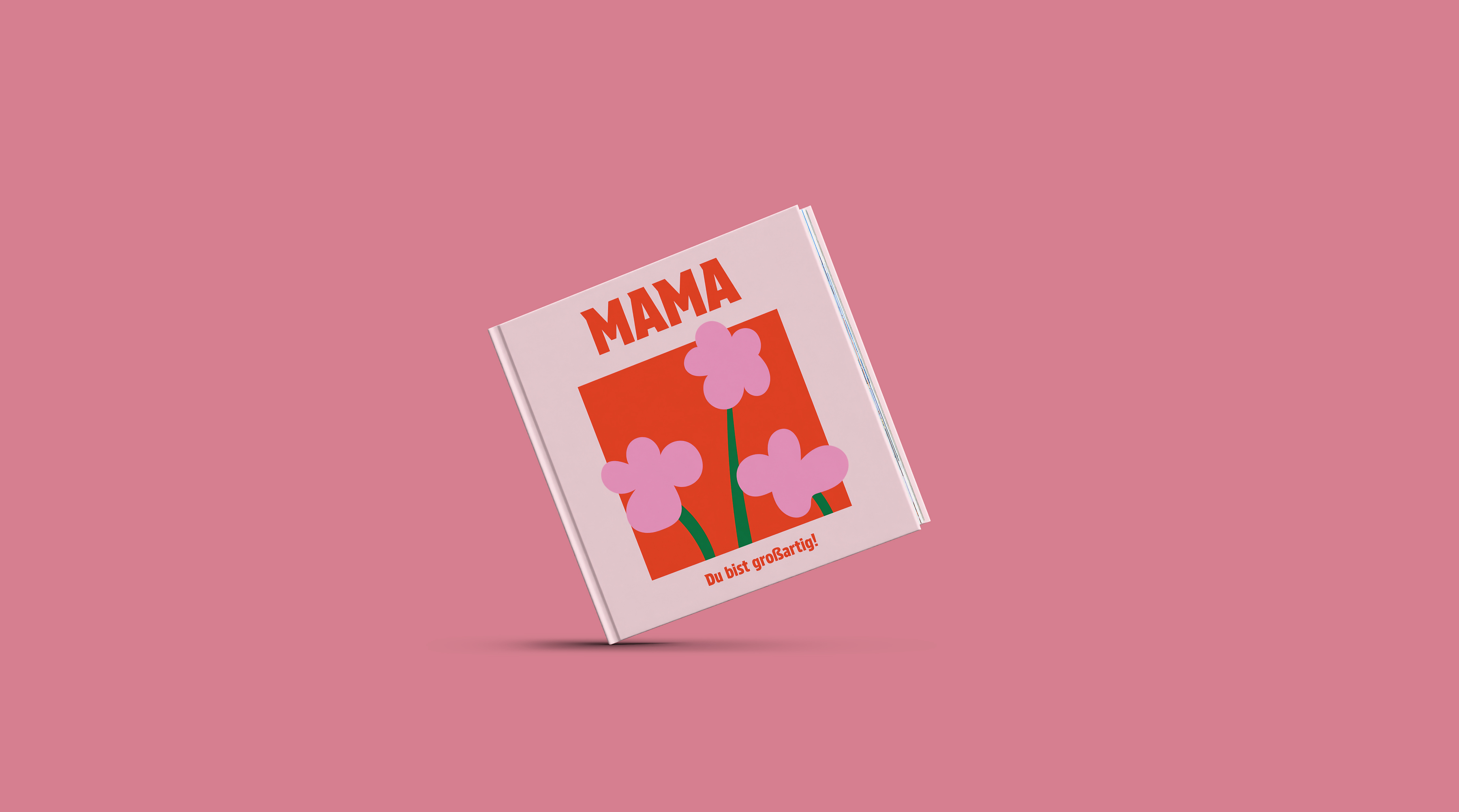 Eine Person hält ein Fotobuch in der Hand. Dieses ist mit rosafarbenen Elementen zum Muttertag gestaltet.