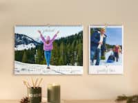 Wandkalender mit Fotos zu Weihnachten verschenken Zwei Fotokalender hängen nebeneinander an einer Wand. Der Raum ist weihnachtlich geschmückt.