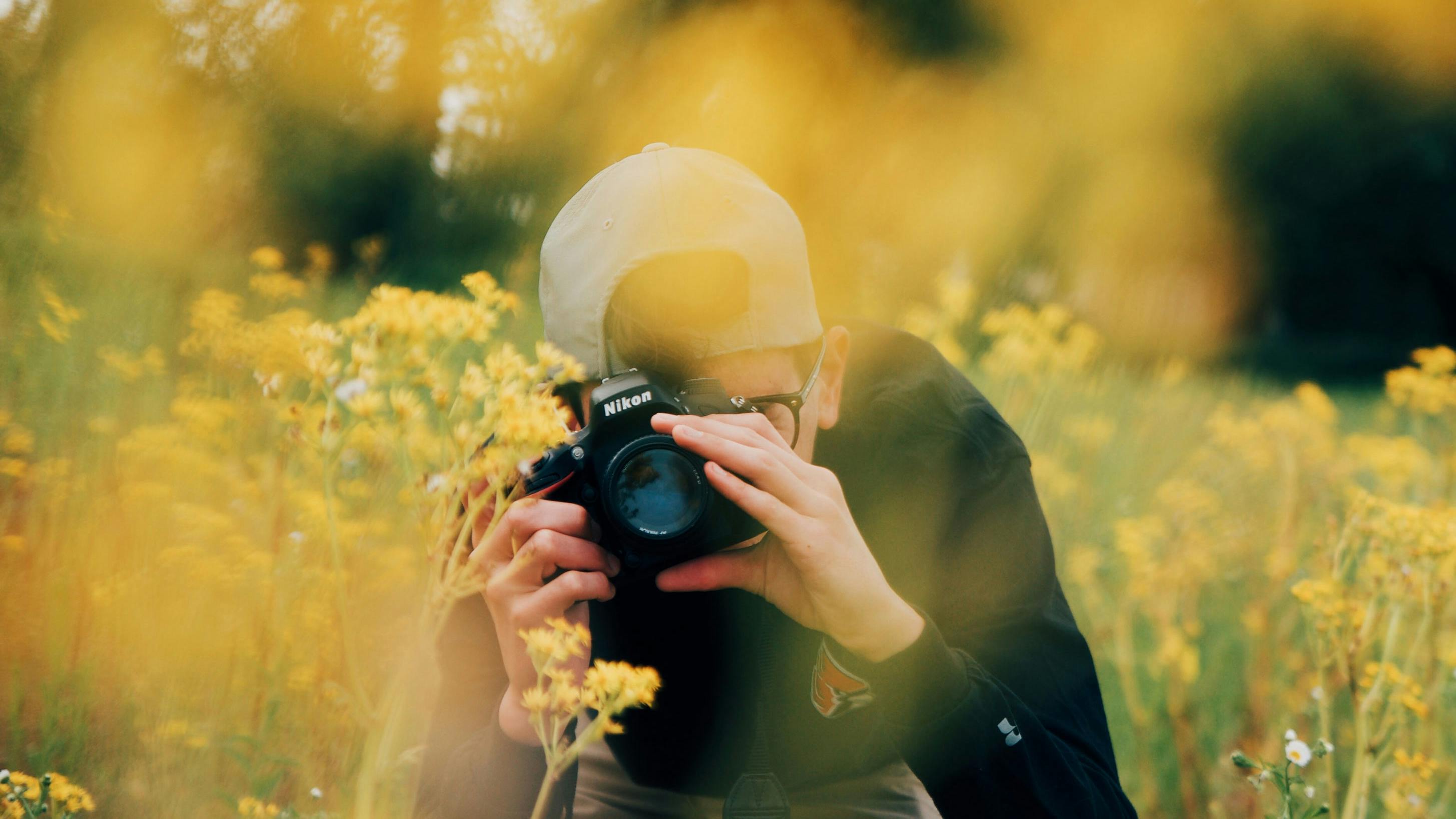 Mann mit Brille fotografiert auf einem Blumenfeld