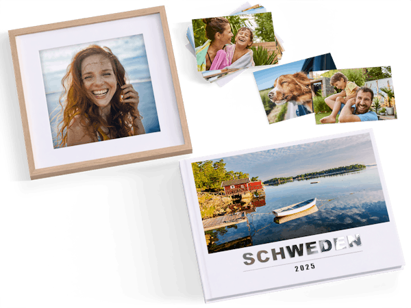 Ein Fotobuch, ein gerahmtes Foto und einige Fotoabzüge mit Urlaubsmotiven liegen nebeneinander