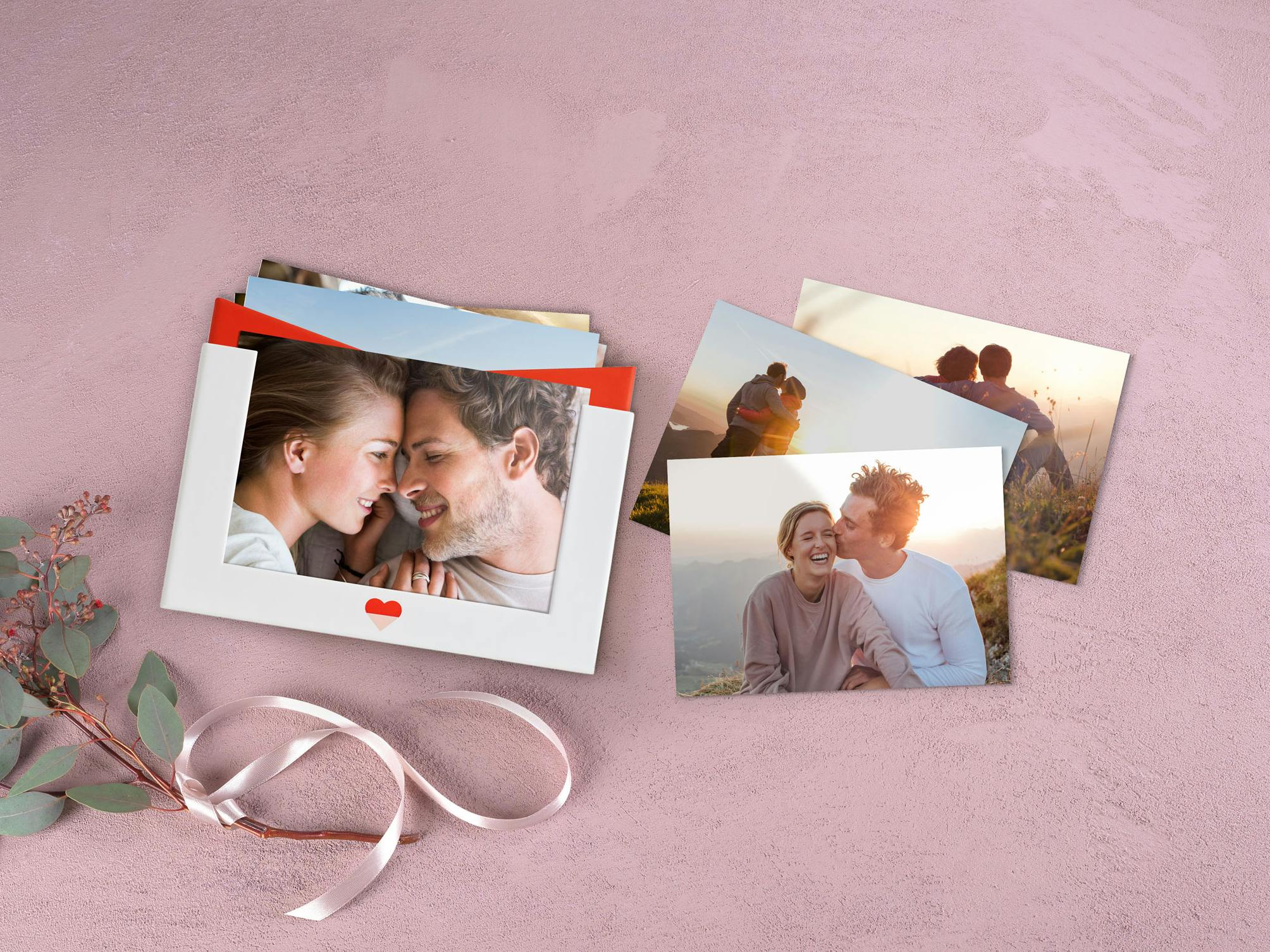 Pixum Fotobox im Liebe-Design auf rosa Hintergrund mit Fotoabzügen eines Pärchens