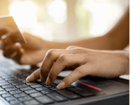 Zahlungsmöglichkeiten Nahaufnahme einer Person, die vor einem Laptop sitzt und eine Kreditkarte in der Hand hält