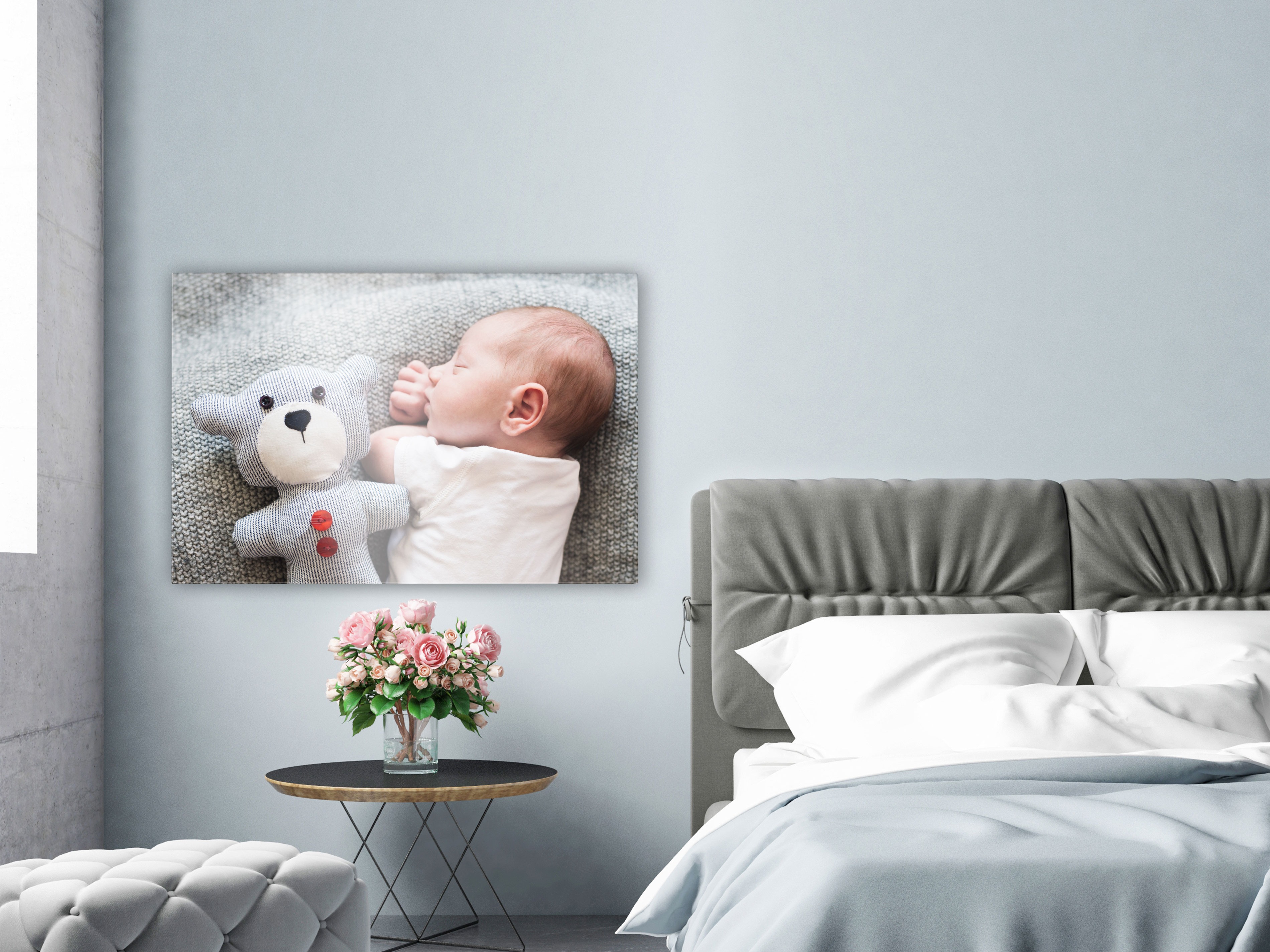 Een canvas met een foto van een slapende baby hangt aan de muur in de woonkamer.