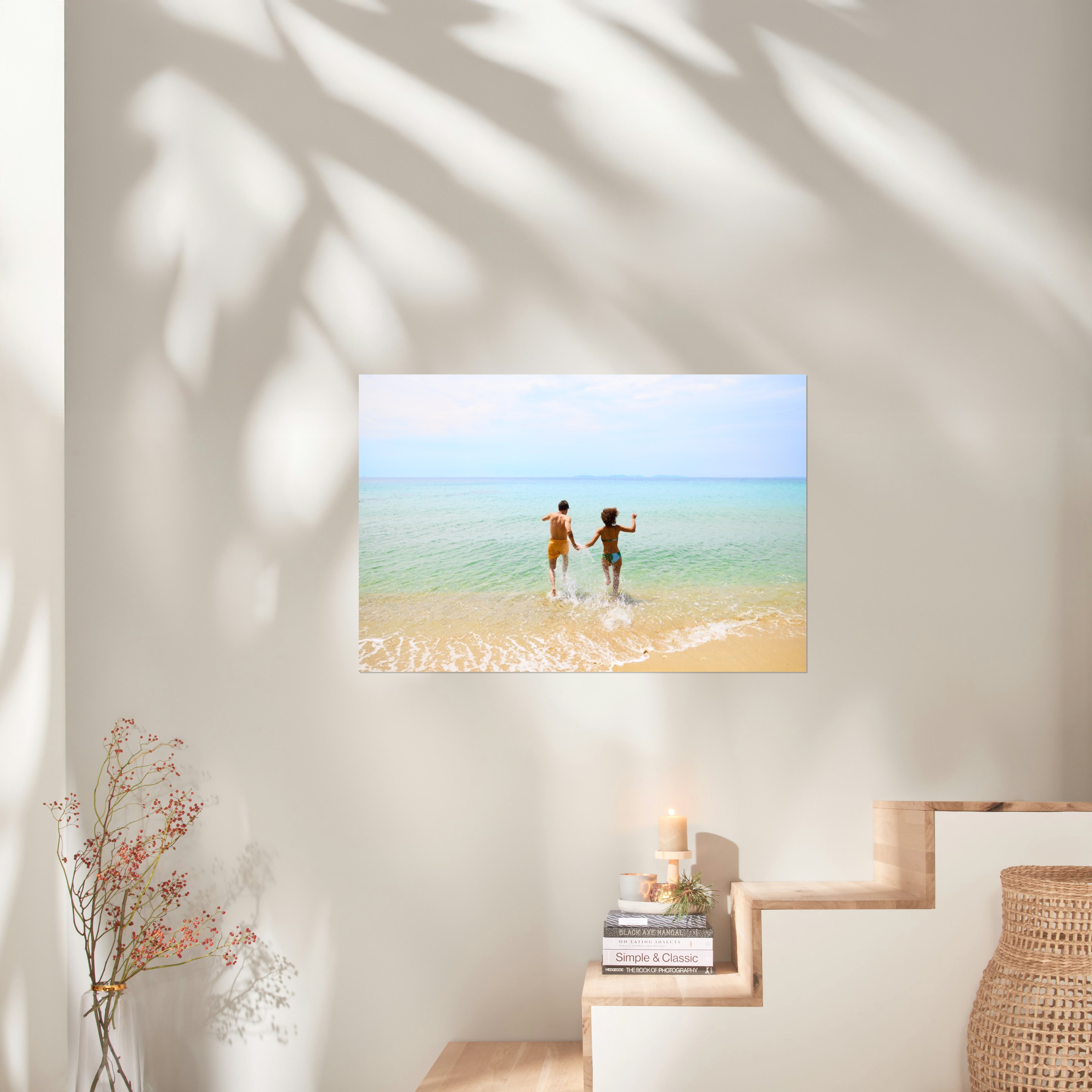 Ein Fotoposter im Format 90x60 cm hängt über einer Treppe und zeigt ein Bild von einem Pärchen, das ins Meer läuft.