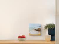 Foto auf Holz als Wandbild drucken Ein Wandbild in dem Maßen 20 zu 20 aus Holz mit einem Urlaubsfoto hängt an einer Wand, über einer Kommode.