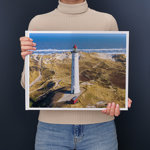 En kvinde holder en XXL fotobog i tværformat med et stort landskab i sine hænder