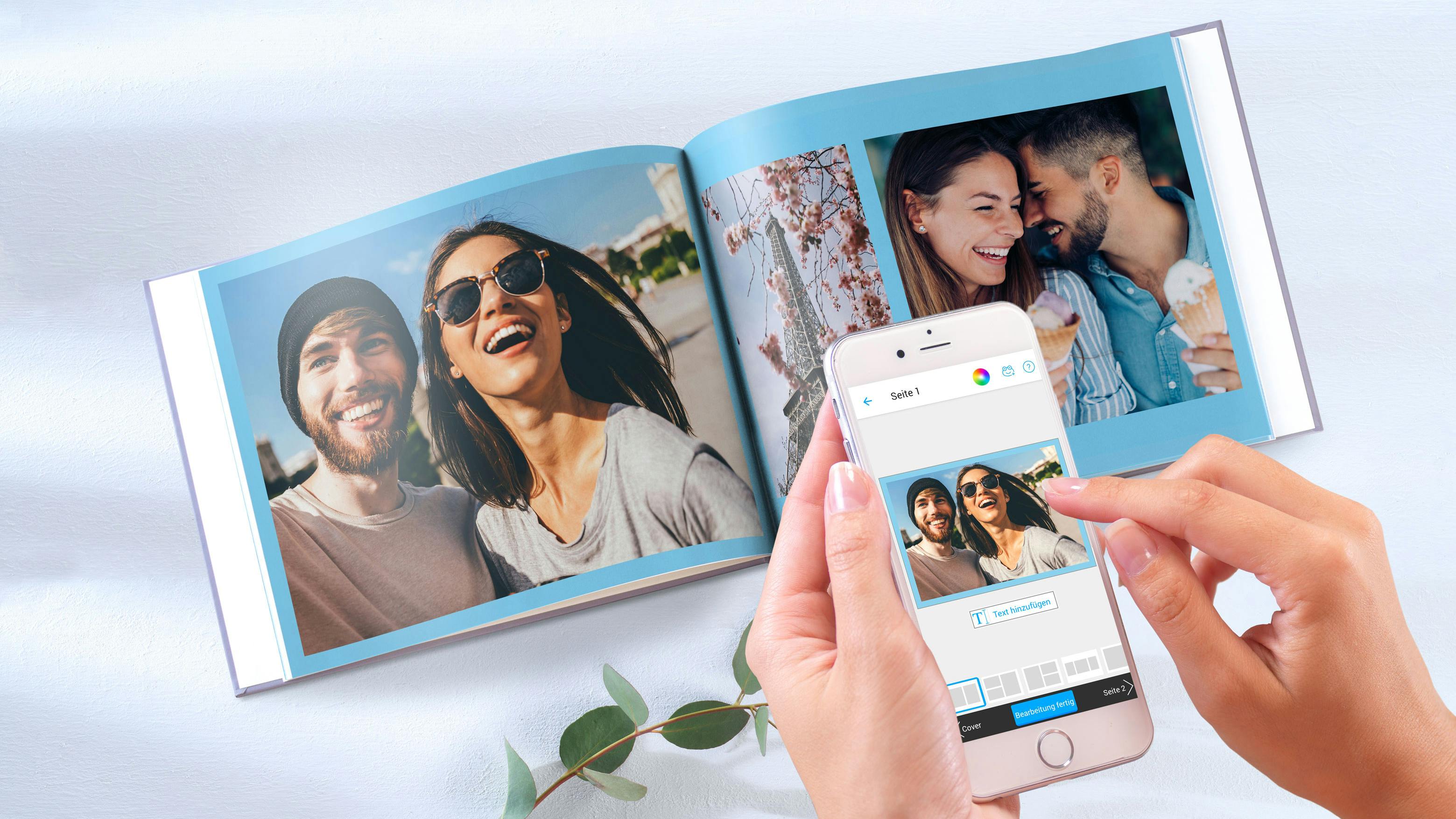 Aufgeschlagenes Fotobuch im Querformat mit frühlingshaften Motiven und hellblauer Hintergrundfarbe, das per Smartphone gestaltet wird